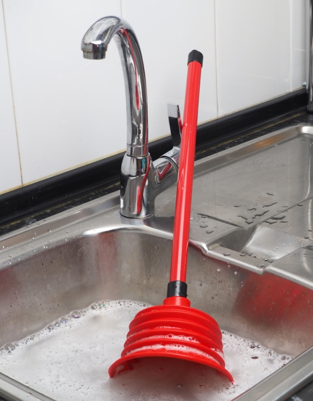 A kitchen sink with a red scrubbing brush for scheduled maintenance.