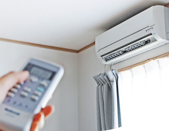 A technician specializing in air conditioner installations holds a remote control for repair and services.